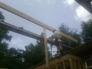 Carpenter setting a ridge beam over a new addition frame — Ice Dam Removal by Roofing Brothers in Cottageville