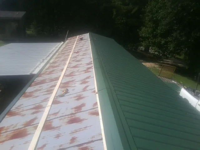 Old rusted panels beside newly installed green metal roofing — Wind Damage Roof Repair by Roofing Brothers in Cottageville