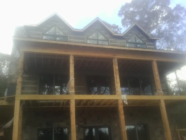 Dormers and porch framing on a large log home under construction — Roof Coating work by our crew in Cottageville