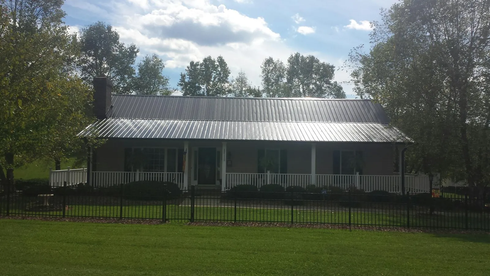 Gray metal roof on a brick ranch with a full width front porch — Gutter Guard Installation work by our crew in Cottageville