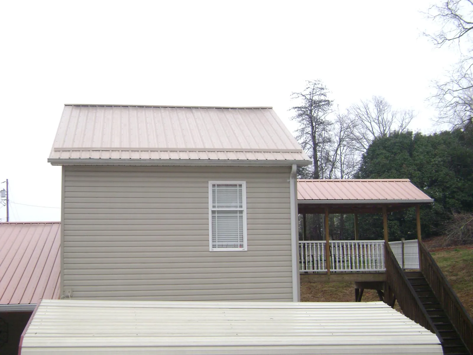 Tan metal roofs on a two story addition and attached porch, from a Roof Replacement job in Cottageville